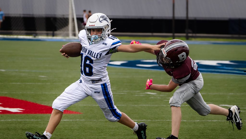 Ball carrier holding off a defender with a stiff arm